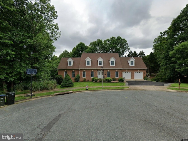 cape cod house featuring a garage, driveway, brick siding, and a front lawn