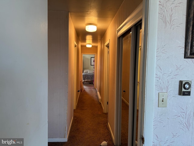 hallway with dark colored carpet and baseboards