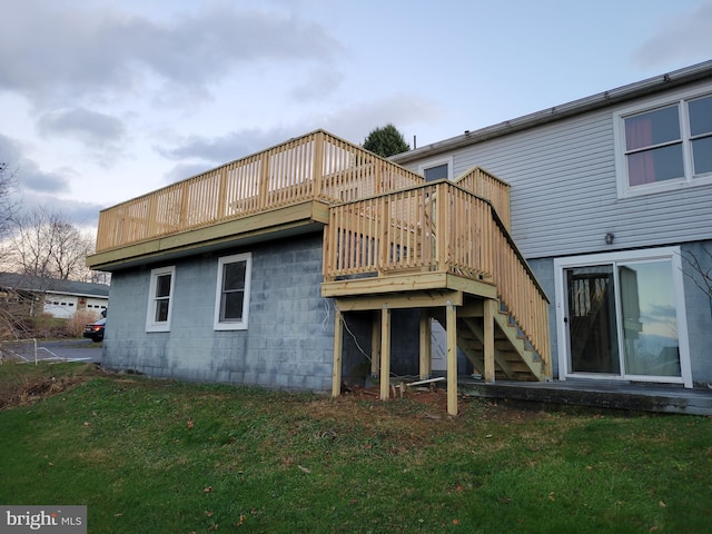 back of property featuring a lawn, a wooden deck, and stairs