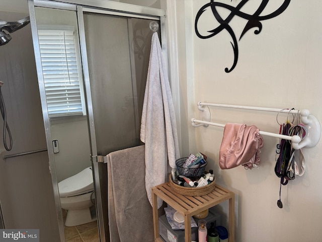 bathroom featuring toilet, a shower stall, and tile patterned floors