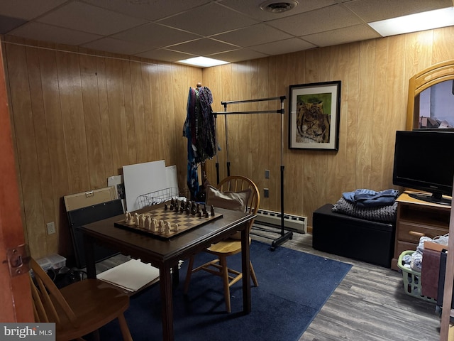 interior space with a baseboard radiator, wooden walls, visible vents, and wood finished floors