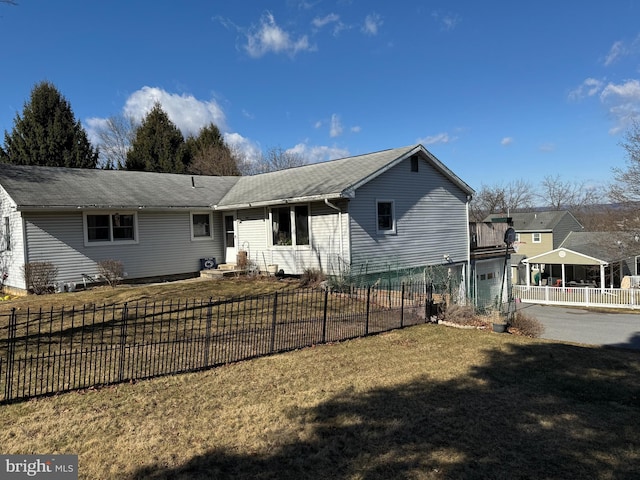 rear view of house featuring a garage, fence private yard, and a lawn