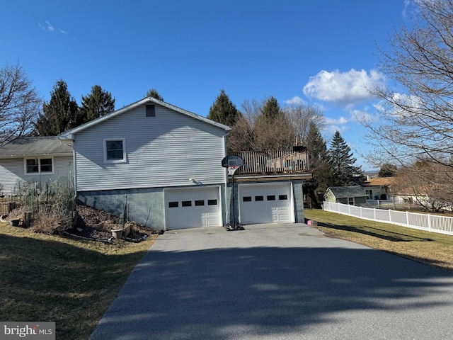 view of property exterior featuring aphalt driveway, a yard, an attached garage, and fence