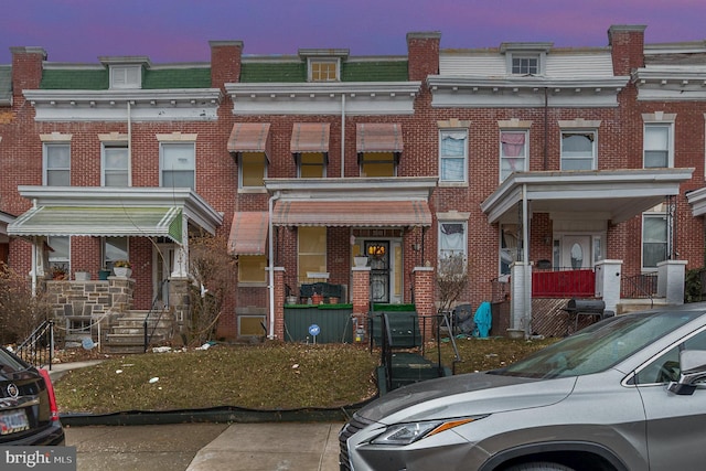 view of property with brick siding and mansard roof