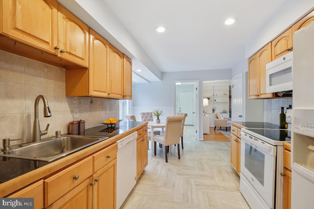 kitchen with white appliances, decorative backsplash, a sink, and recessed lighting