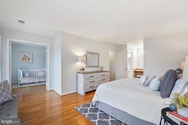 bedroom featuring visible vents, light wood-style flooring, and baseboards