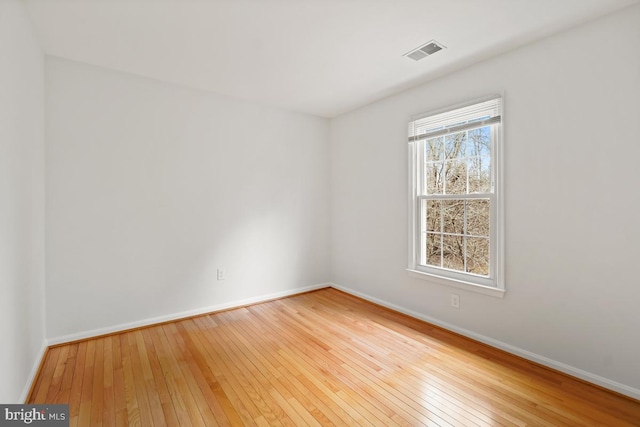 unfurnished room featuring wood-type flooring, visible vents, and baseboards