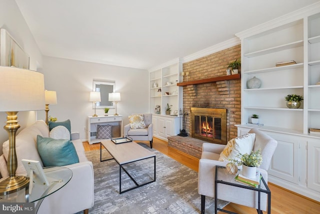 living room featuring built in shelves, a brick fireplace, and light wood-style flooring