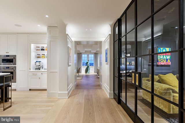 hall featuring light wood-style flooring and baseboards