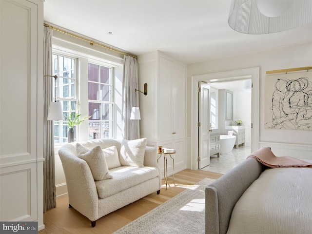 bedroom with multiple windows, ensuite bath, and light wood-style floors