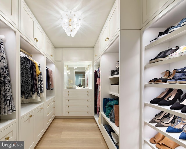 walk in closet featuring a chandelier and light wood-style flooring