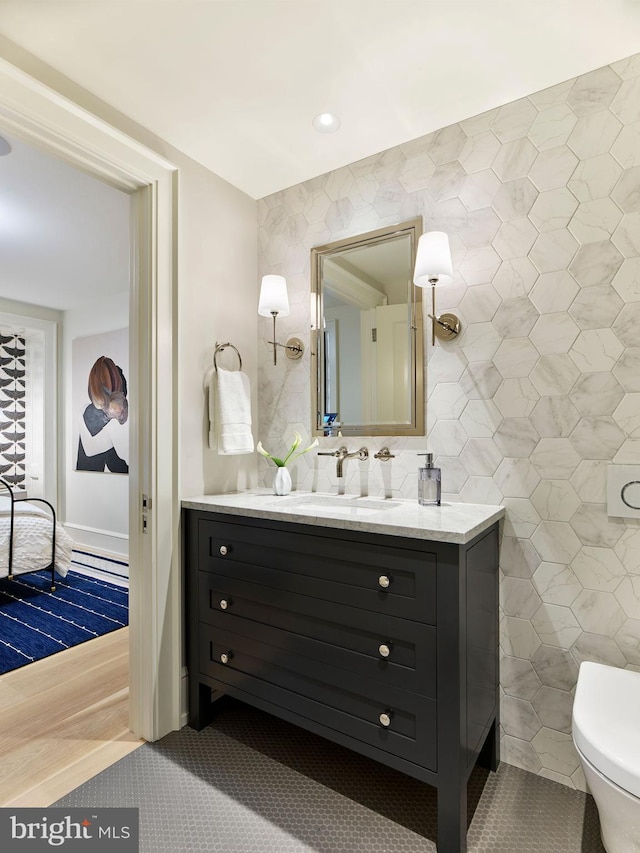 bathroom with toilet, tile walls, vanity, and tile patterned floors