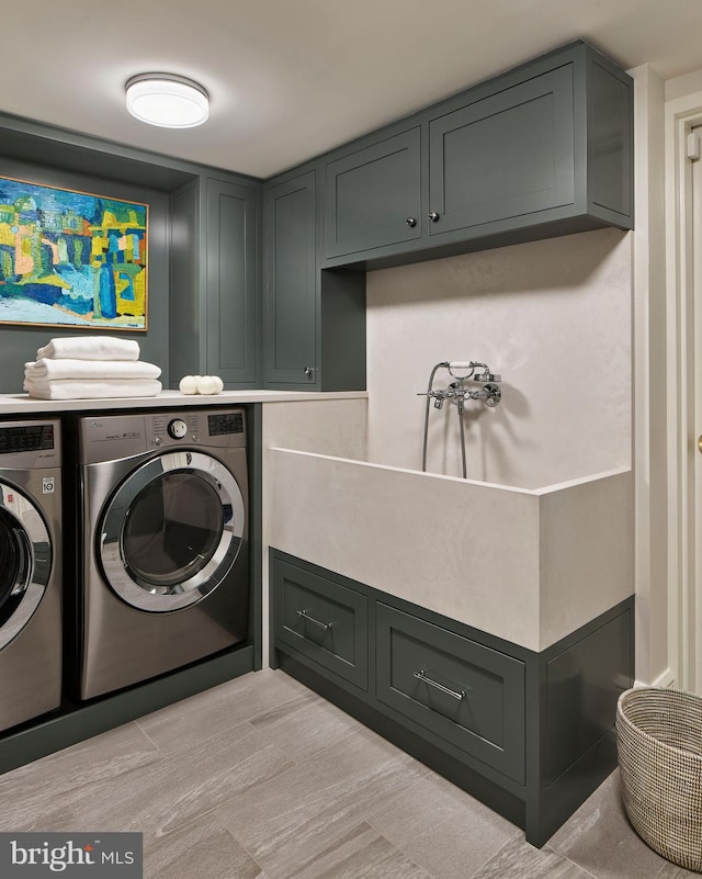 washroom featuring cabinet space and washer and clothes dryer