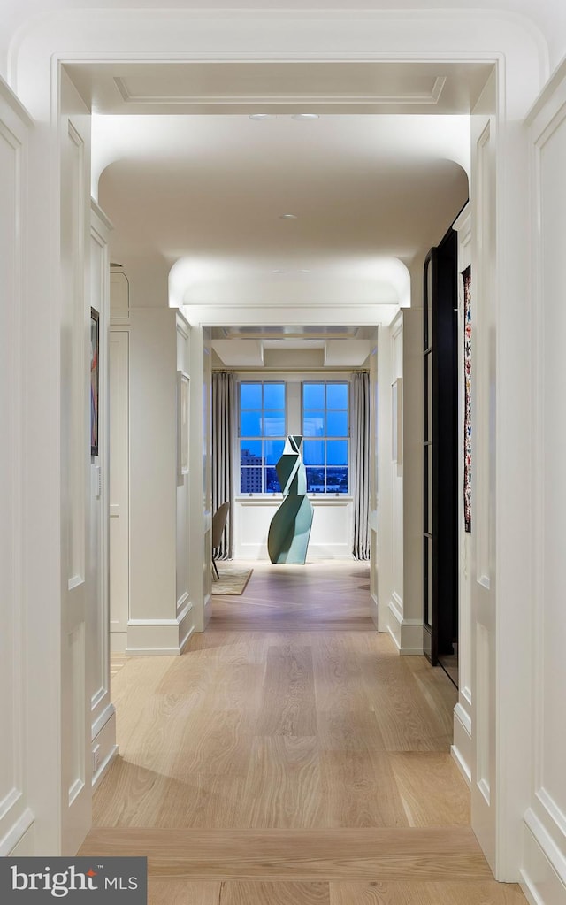 hall with light wood-style flooring and baseboards