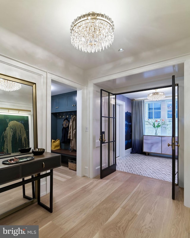 hall with light wood-type flooring and an inviting chandelier