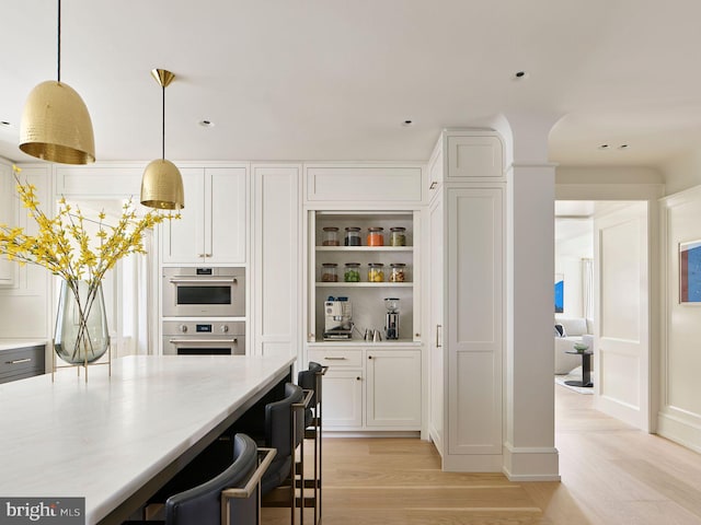 kitchen with white cabinets, pendant lighting, stainless steel double oven, light wood-type flooring, and open shelves