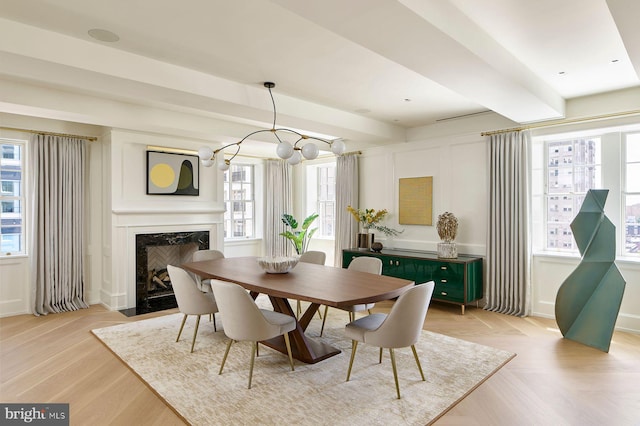 dining space featuring a fireplace, parquet flooring, and beam ceiling