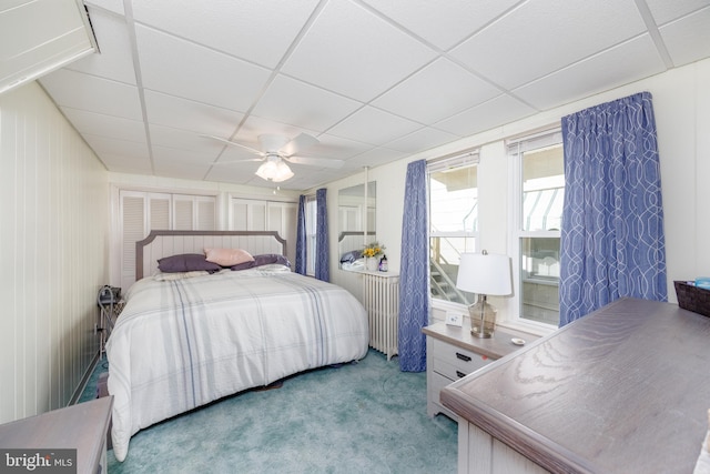 bedroom featuring light carpet, a drop ceiling, and a ceiling fan