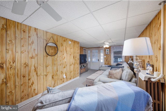 living area featuring ceiling fan, radiator heating unit, carpet flooring, and wooden walls