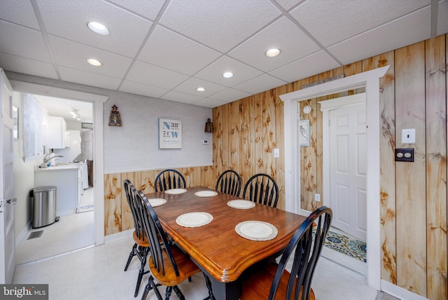 dining room featuring a drop ceiling, recessed lighting, and wooden walls