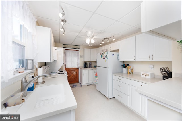 kitchen with white appliances, light countertops, track lighting, and white cabinets