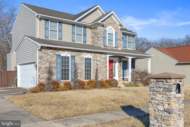 view of front of house with stone siding, a shingled roof, fence, and concrete driveway