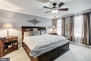 bedroom with light carpet, a ceiling fan, and crown molding