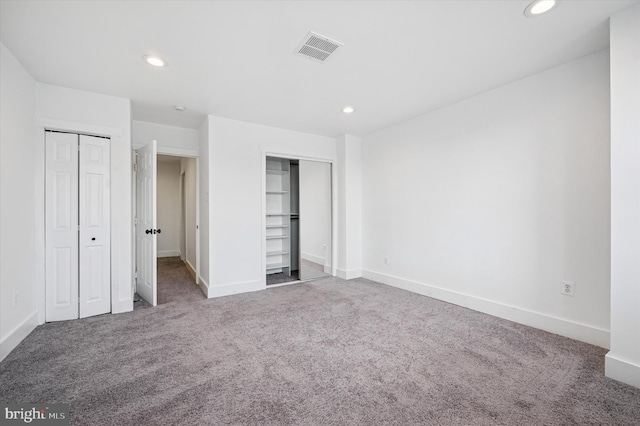 unfurnished bedroom featuring carpet flooring, two closets, visible vents, and recessed lighting