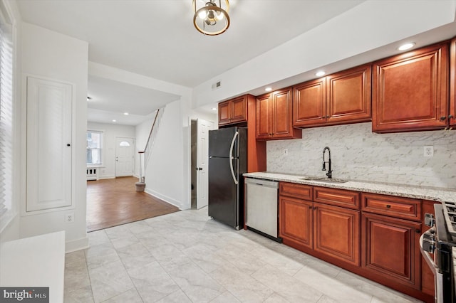 kitchen with light stone countertops, decorative backsplash, stainless steel appliances, and a sink