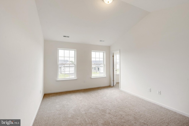 carpeted empty room with visible vents, baseboards, and vaulted ceiling