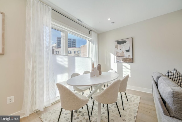 dining area with light wood-style floors, visible vents, and baseboards