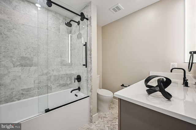 bathroom with toilet, bath / shower combo with glass door, vanity, and visible vents