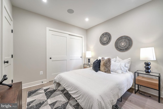 bedroom featuring a closet, recessed lighting, wood finished floors, and baseboards