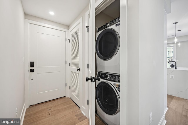 laundry area featuring stacked washer and dryer, light wood finished floors, laundry area, and recessed lighting