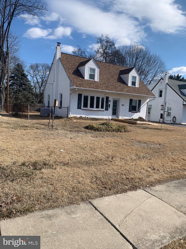 cape cod home with a shingled roof, fence, stucco siding, a front lawn, and a chimney