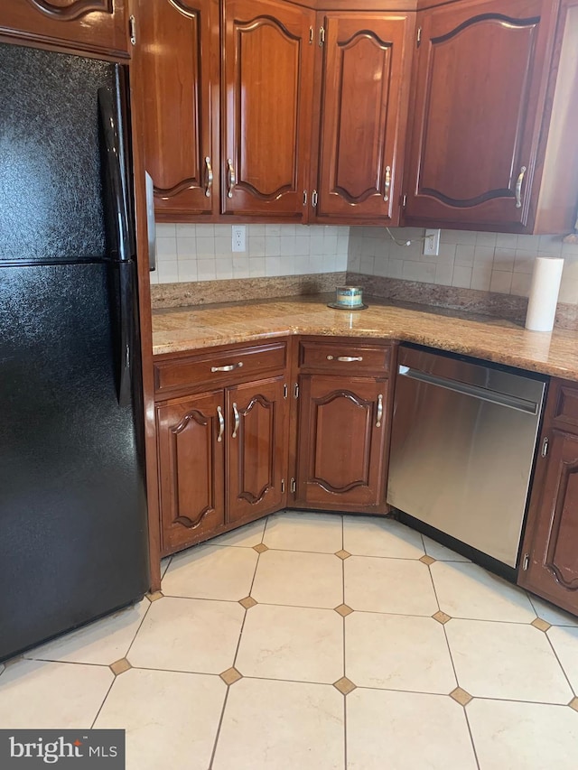 kitchen featuring stainless steel dishwasher, freestanding refrigerator, and tasteful backsplash