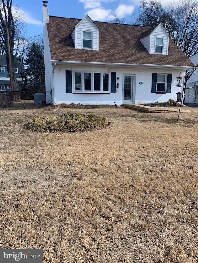 cape cod home featuring a shingled roof, fence, a chimney, and a front lawn