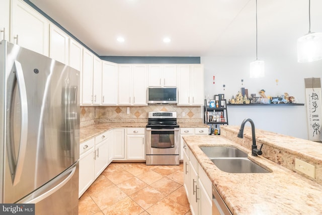 kitchen with a sink, decorative backsplash, white cabinets, appliances with stainless steel finishes, and decorative light fixtures