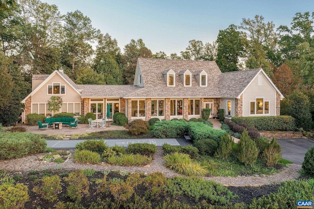 cape cod house featuring a patio area and outdoor lounge area