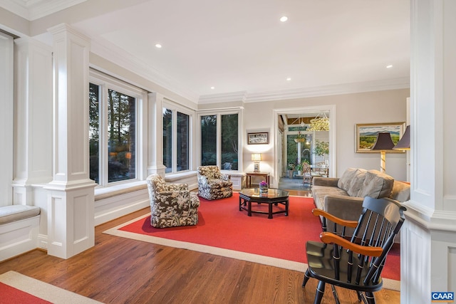 living area featuring ornate columns, crown molding, wood finished floors, and recessed lighting