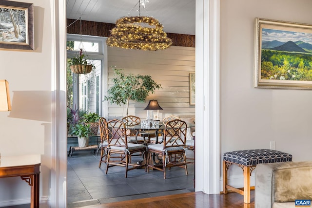 dining area with wood walls and a chandelier