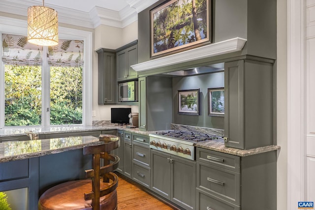 kitchen featuring stainless steel appliances, gray cabinets, light stone countertops, built in desk, and crown molding