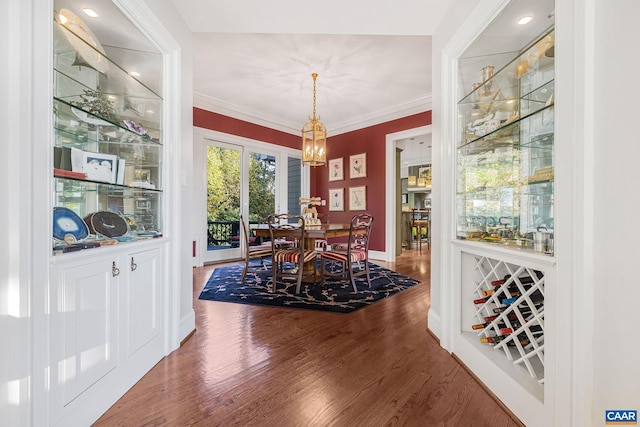 dining space featuring a chandelier, ornamental molding, wood finished floors, and baseboards