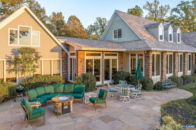 back of house with a patio, an outdoor hangout area, stone siding, french doors, and roof with shingles