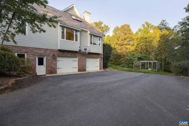 exterior space featuring a garage, driveway, and brick siding