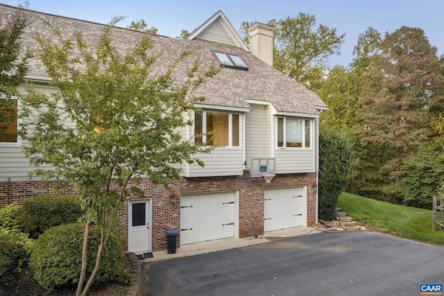 view of front facade with driveway, roof with shingles, an attached garage, and brick siding