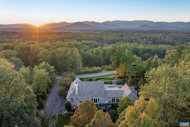 aerial view at dusk with a mountain view and a wooded view