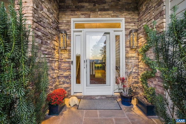 doorway to property featuring stone siding and brick siding