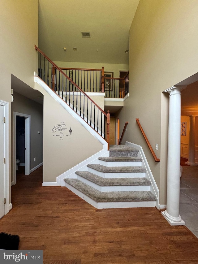 staircase with baseboards, visible vents, ornate columns, and wood finished floors