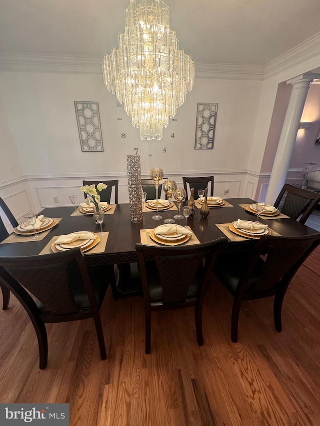 dining area featuring a wainscoted wall, decorative columns, crown molding, and wood finished floors